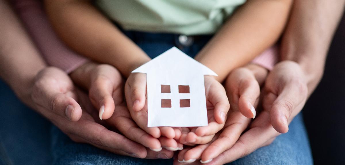Mains grand-parents, parents et enfant tenant une maison symbolisant la donation pour l'achat d'un logement neuf